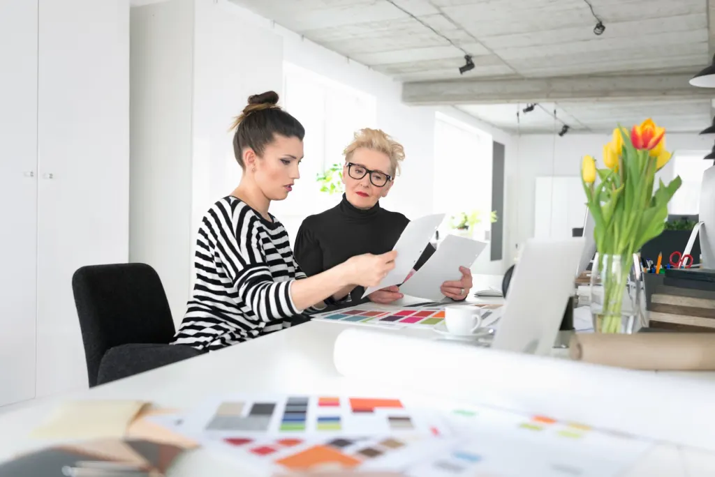 Designer and homeowner reviewing drawings and finish samples at a studio table
