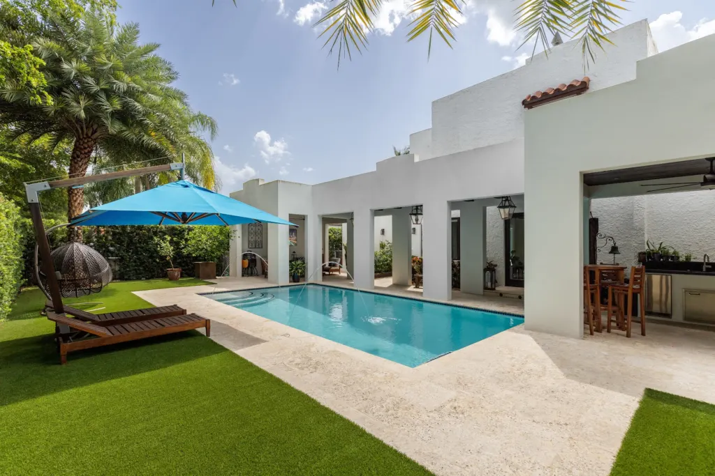 Pool deck with pavers, artificial turf, and a shaded lounge in a Miami backyard