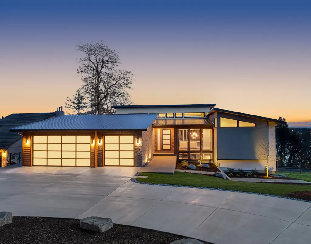 Concrete driveway and lit facade of a modern home at dusk