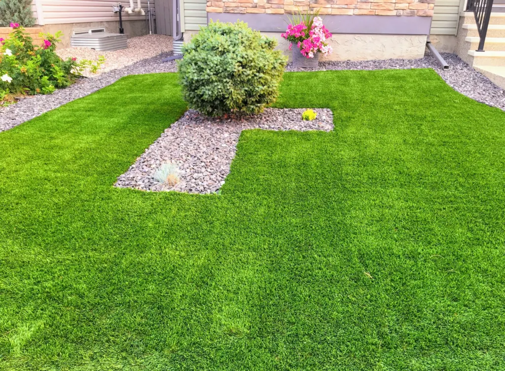 Artificial lawn with a raised planting bed and pebble border