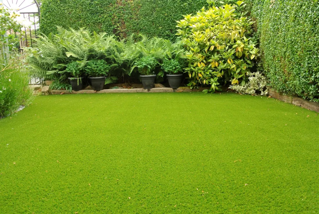Artificial turf lawn framed by hedging and container plants