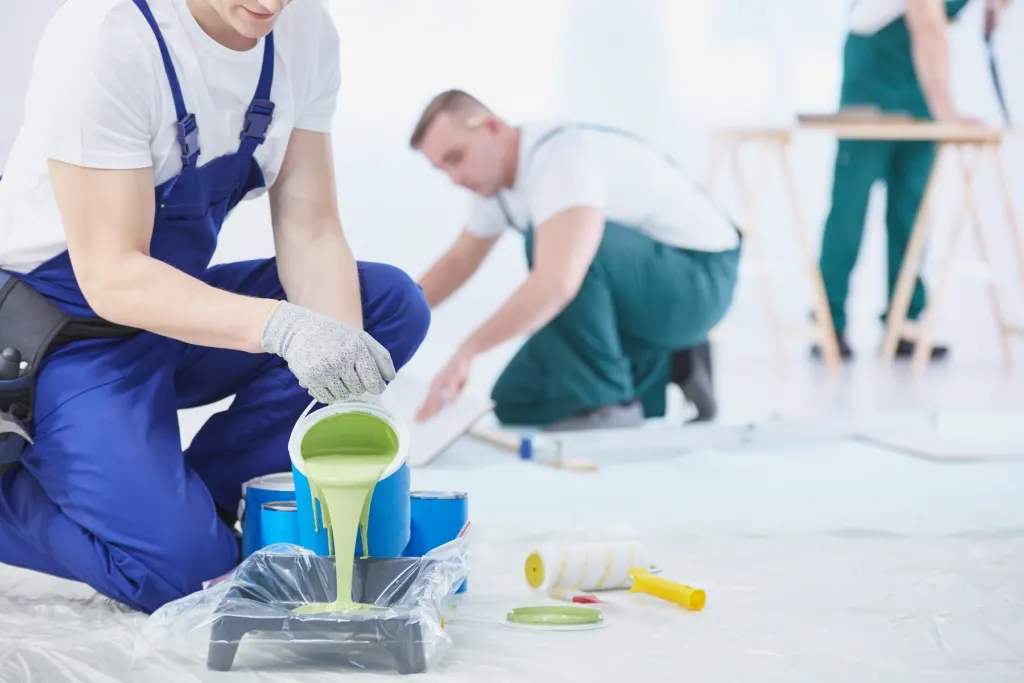 Painters mixing and pouring paint on a protected floor