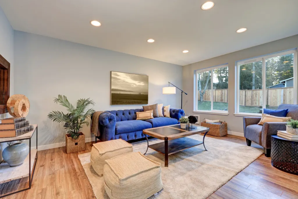 Living room with pale walls, a blue sofa, and wood floors