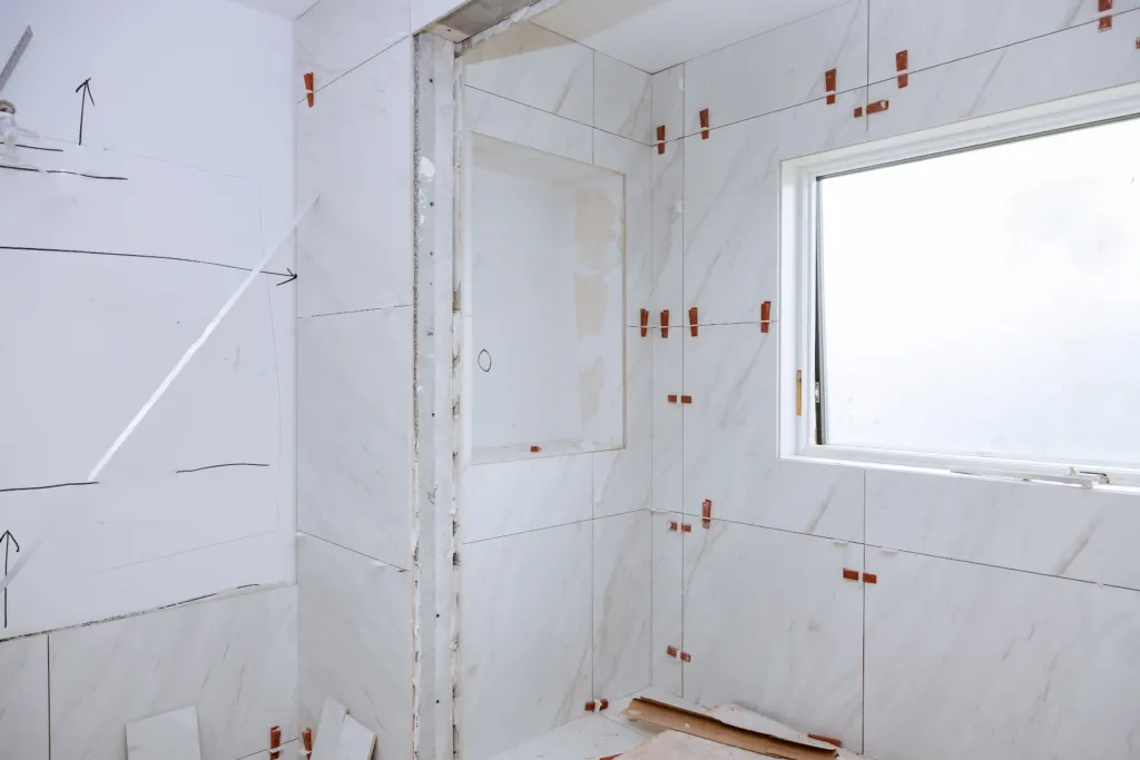 Large-format marble wall tile being set in a shower enclosure